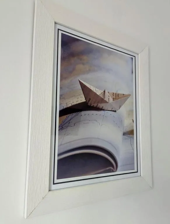 Um quadro na parede: um barco de papel sobre um livro aberto